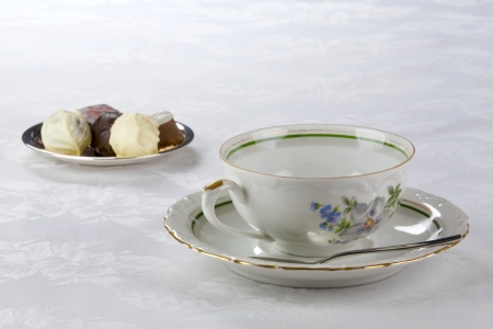Tea cup, saucer and candies made of black and white chocolateの写真素材