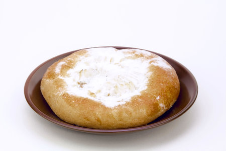 Cheese cake on a brown saucer, dusted with icing sugar