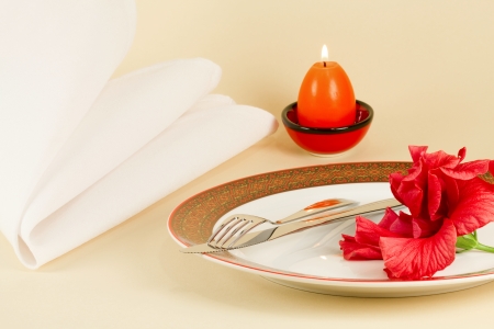 Table setting by Easter - a dish with knife and fork decorated with red flower, Easter candle and napkinの写真素材