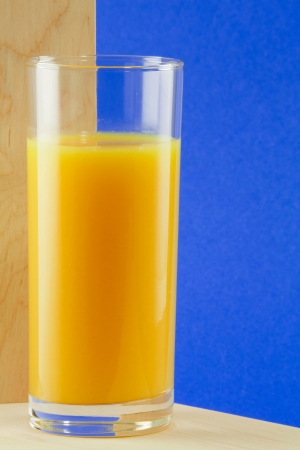 A tall glass with orange juice, blue backgroundの写真素材