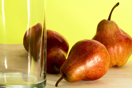 Ripe pears and empty transparent glass on yellow backgroundの写真素材