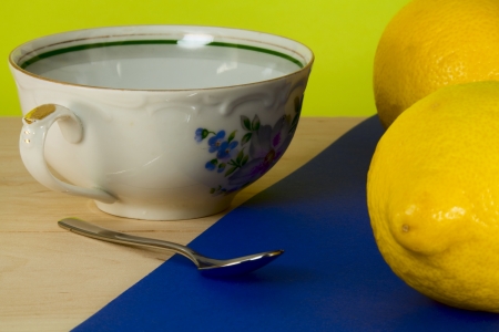 Tea cup, a spoon and a lemon on a colored backgroundの写真素材