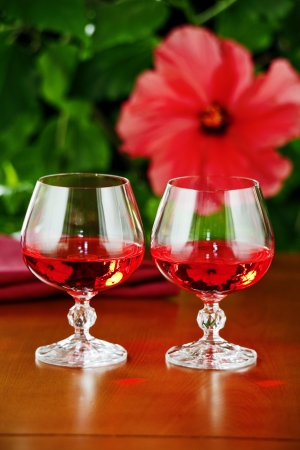 On the table glasses of red wine , the background - a flowering plantの写真素材
