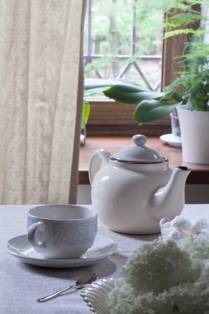 Teacup on saucer, teapot and sweetsの写真素材