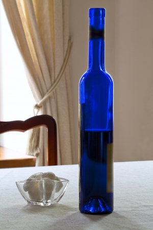 On a table near the window - a bottle with wine and sweetsの写真素材