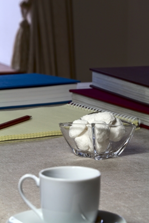 On a table a small vase with candies, notebook and booksの写真素材