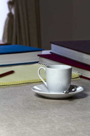On a table near the window - coffee cup, notebook and booksの写真素材