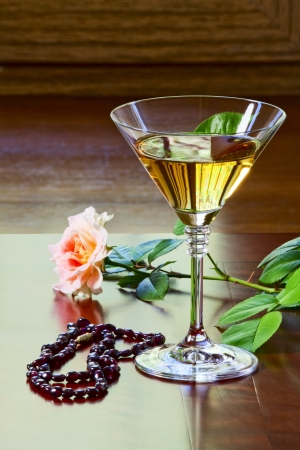 Garnet necklace, glass with white wine and a rose on an old tableの写真素材