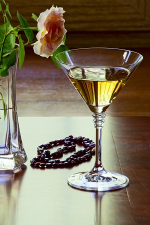 Garnet necklace, glass with white wine and a rose in a glass vase on an old tableの写真素材