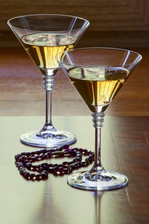 Garnet necklace and two glasses with white wine on an old tableの写真素材