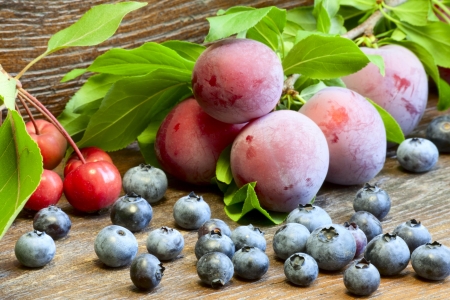 Blueberry, plums and wild apples on a wooden backgroundの写真素材