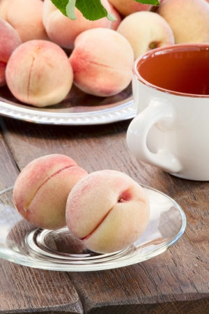 Goldish velvety ripe peaches on a glass saucerの写真素材