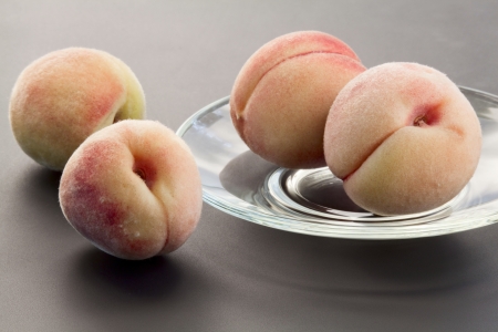 Goldish velvety ripe peaches on a glass saucerの写真素材