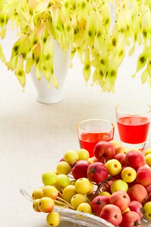On a table wild apples in a glass vase and small glasses with liquorの写真素材