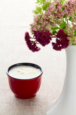 A cup of milk and a bouquet of autumn flowers in a vaseの写真素材
