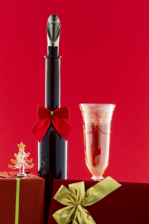 Bottle decorated with a Christmas bowknot a glass of wine and boxes with giftsの写真素材