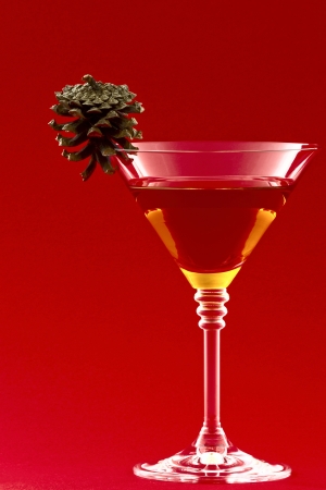 Glass with a cocktail and a pine cone on a red backgroundの写真素材