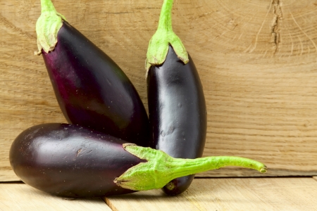 Group of three ripe eggplants on a wooden backgroundの写真素材