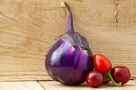 Rounded ripe eggplant and red bitter peppersの写真素材