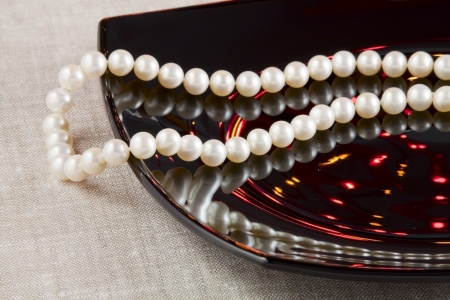 Pearl necklace and black ceramic dishの写真素材