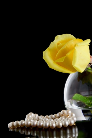 Pearls and yellow rose in a vase on a black backgroundの写真素材