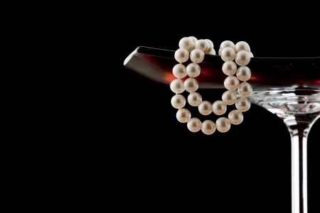 A pearl necklace in black glass vase isolated on blackの写真素材