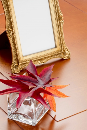 Autumn leaves in a glass vase and a photo frame in retro styleの写真素材