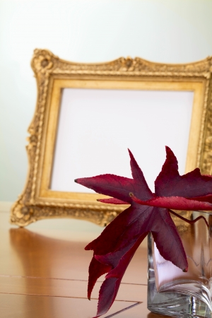 Autumn leaves in a glass vase and a photo frame in retro styleの写真素材
