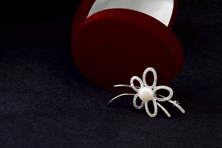 Silver brooch with pearls on a black background