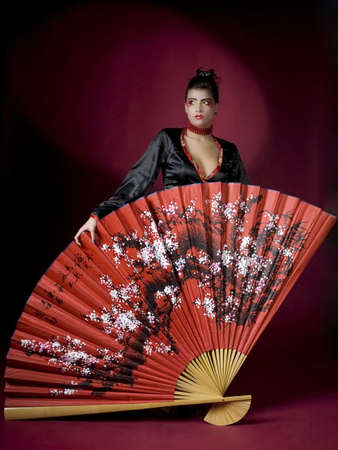 Geisha in studio with huge fanの写真素材