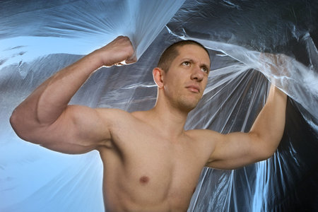 Studio image of a young muscular man on abstract blue background
