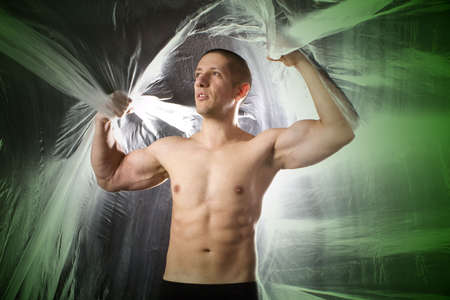 Studio image of a young muscular man on abstract green backgroundの写真素材