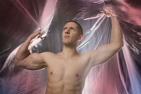 Studio image of a young muscular man on abstract colored backgroundの写真素材