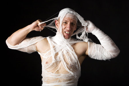 Studio image of a young man bandaged, on black background. Concept for health-care or ancient mummyの写真素材
