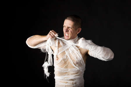 Studio image of a young man bandaged, on black background. Concept for health-care or ancient mummyの写真素材
