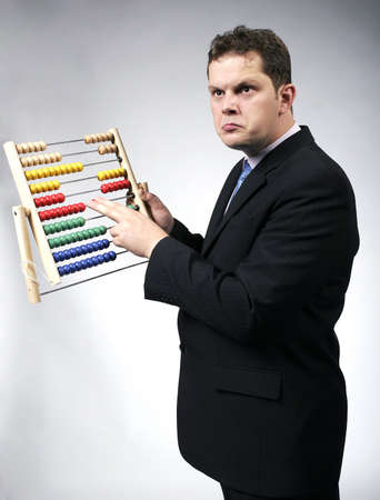 Confused businessman calculating with a multicolor abacus. Studio shot.の写真素材