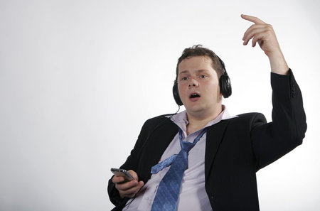 Happy businessman singing and listening to his mp3 player. Studio shotの写真素材