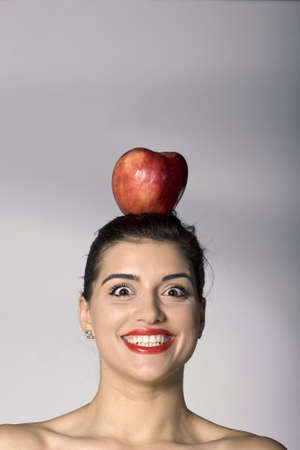 Part of photo series of a woman holding an apple on her headの写真素材