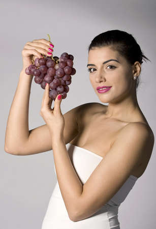 Part of photo series . Woman with red grapes. Studio shotsの写真素材