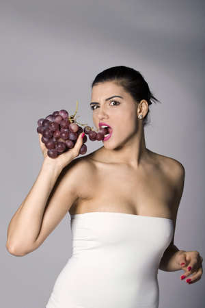 Part of photo series . Woman with red grapes. Studio shotsの写真素材