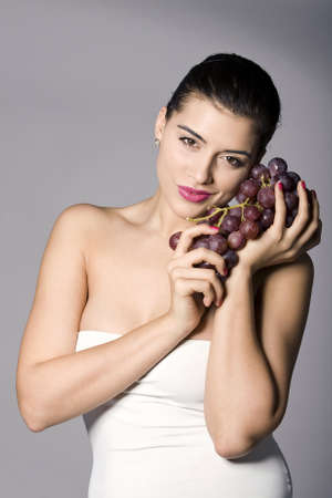 Part of photo series . Woman with red grapes. Studio shotsの写真素材