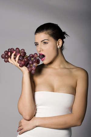 Part of photo series . Woman with red grapes. Studio shotsの写真素材