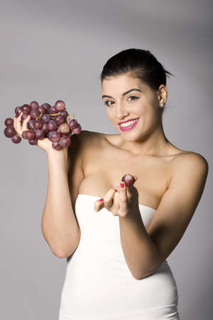 Part of photo series . Woman with red grapes. Studio shotsの写真素材