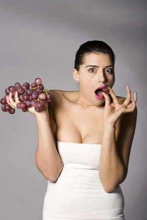 Part of photo series . Woman with red grapes. Studio shotsの写真素材