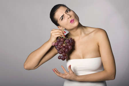 Part of photo series . Woman with red grapes. Studio shotsの写真素材