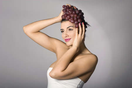 Part of photo series . Woman with red grapes. Studio shotsの写真素材