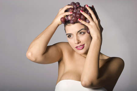 Part of photo series . Woman with red grapes. Studio shotsの写真素材