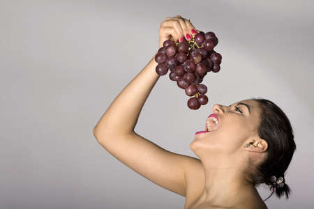 Part of photo series . Woman with red grapes. Studio shotsの写真素材