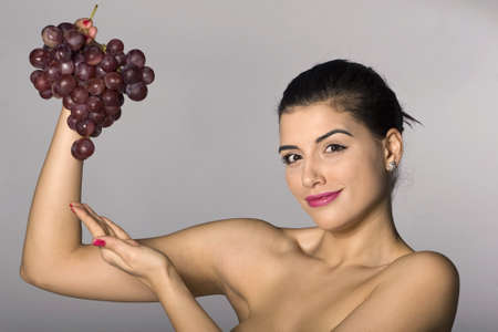 Part of photo series . Woman with red grapes. Studio shotsの写真素材