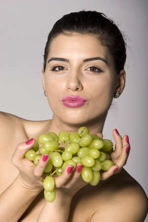 Part of photo series of a woman enjoying fresh green grapes. Studio shotの写真素材